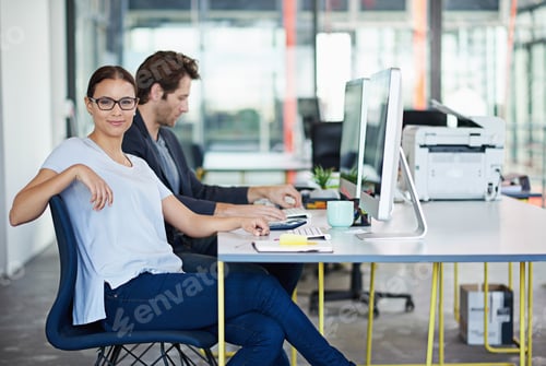 Preview: Portrait of a woman with her male colleague sitting at computers in a large office