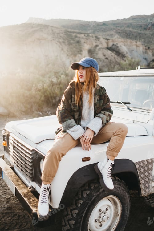Preview: Young woman on casual wear sitting on car