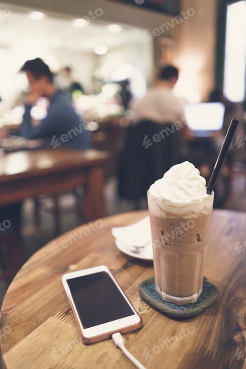 Preview: Cellphone and drinks on wooden table in coffee shop