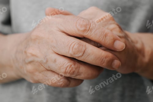 Preview: Folded wrinkled hands of an older caucasian woman, veins and moles close-up. Concept of loneliness
