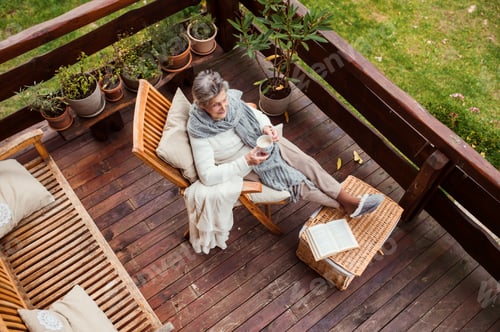 Preview: A top view of elderly woman with a book outdoors on a terrace in autumn.