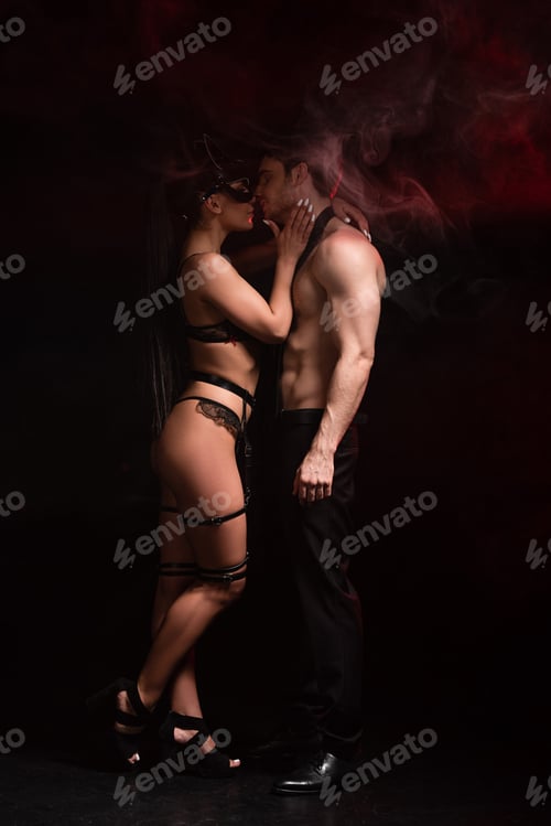Preview: side view of sexy girl in lingerie and mask gently touching boyfriend on black
