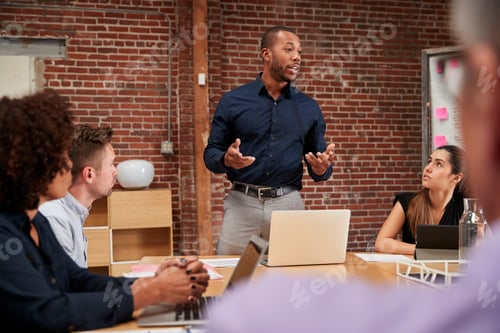 Preview: Businessman Standing And Leading Office Meeting Around Table