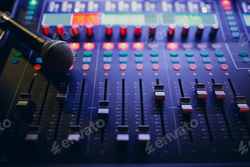 Preview: Mixing console and microphone, hand equalizing audio sound channels in night club