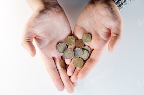 Preview: man hands holding a heap of coins in his hands above brown white table,