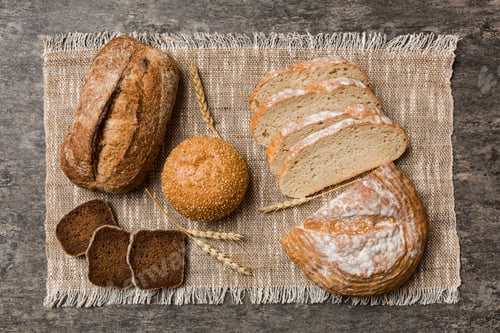 Preview: Freshly baked bread slices on napkin against natural background. top view Sliced bread