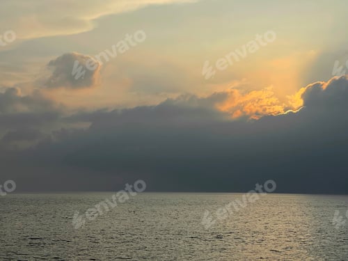 Preview: Beautiful sunset on the sea, the sun sets behind a large cloud lying on the water