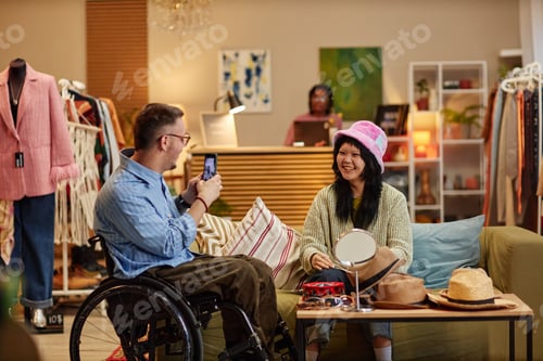 Preview: Caucasian Man with Disability Photographing Young Asian Woman in Second Hand Shop