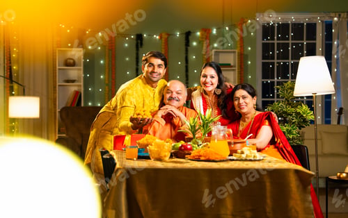 Preview: Smiling Indian family of four enjoys Diwali evening with sweets at decorated indoor table