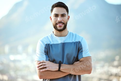 Preview: Portrait of a sporty young man standing with his arms crossed while exercising outdoors