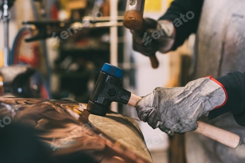 Preview: Hands of metalworker hammering copper in forge workshop