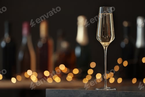 Preview: Glass of champagne on table against blurred background. Space for text