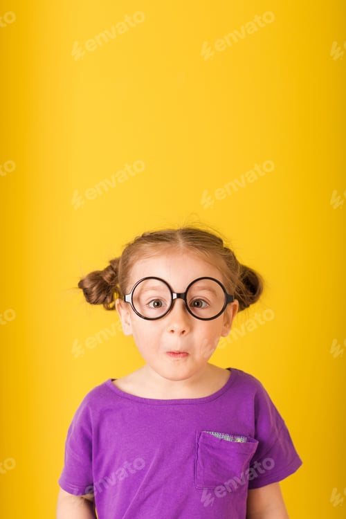 Preview: Little cute caucasian funny surprised kid child baby girl with glasses in purple T-shirt