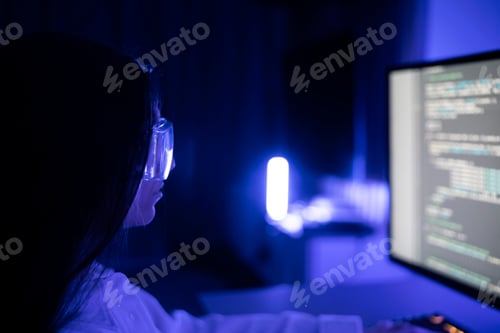 Preview: Female Software Developer Concentrating on Coding Project at Workplace During Nighttime