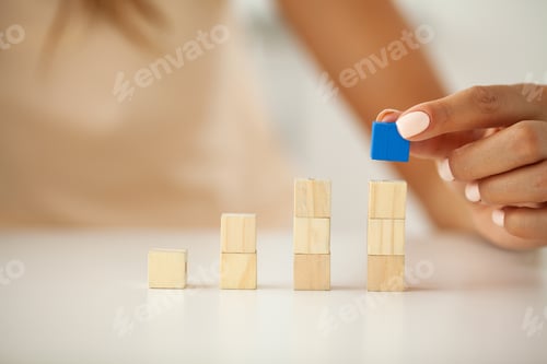 Preview: Woman hand putting and stacking blank wooden cubes on desk with copy space