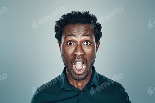 Preview: Surprised young African man looking at camera and keeping mouth open