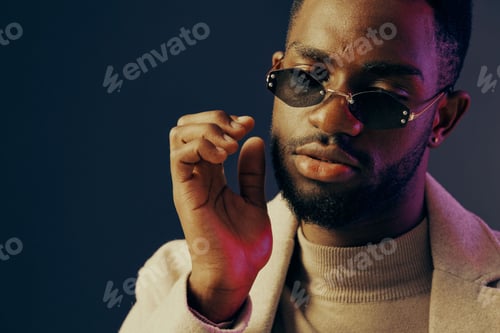 Preview: Stylish young man with sunglasses expressing confidence against a dark blue background, showcasing