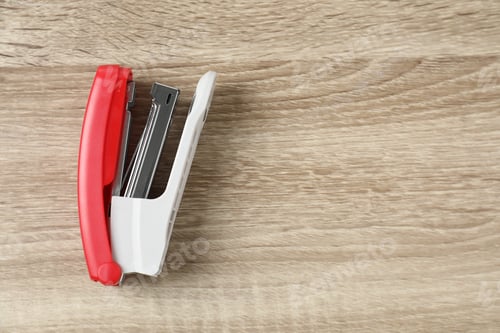 Preview: Bright stapler on wooden table, top view. Space for text