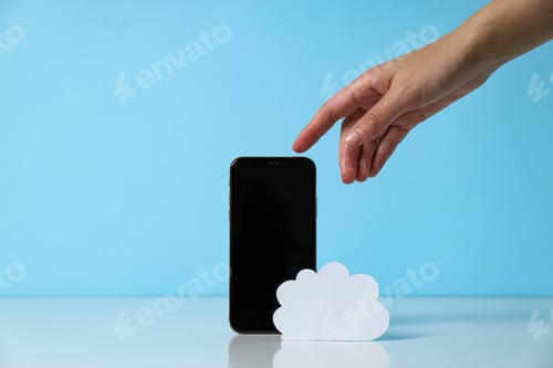 Preview: Black smartphone with paper white cloud and hand on blue background