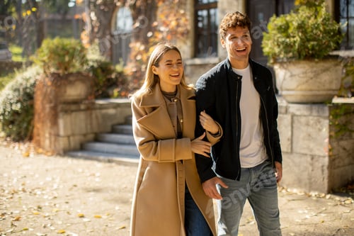 Preview: Couple enjoys a sunny autumn walk with laughter in a charming park setting
