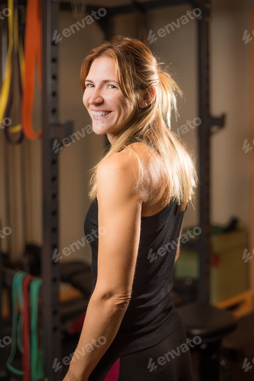 Preview: Rear side view of woman in gym looking at camera