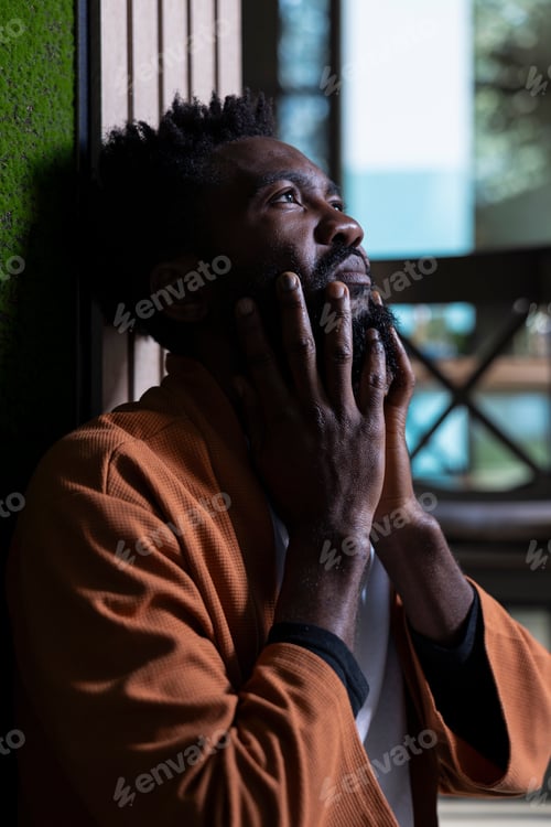 Preview: Sad African American man in silent solitude sitting on the floor