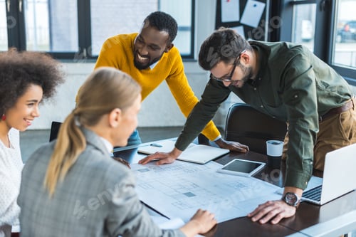 Preview: happy multicultural businesspeople with blueprint in office