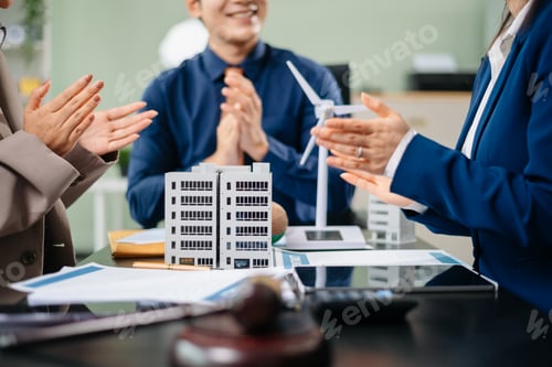 Preview: Group of professionals brainstorming with wind turbine and city model for sustainable energy