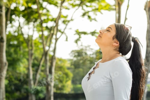 Preview: beautiful latina woman, outdoors raising her head to breathe the fresh air of nature