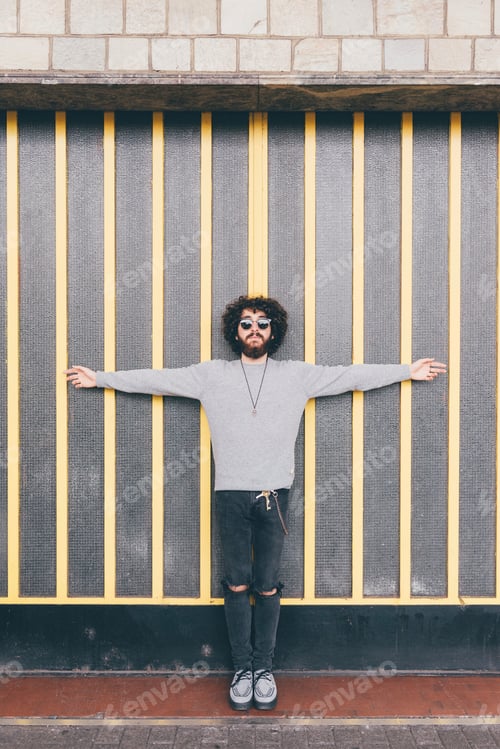 Preview: Portrait of young man, arms outstretched, in urban environment