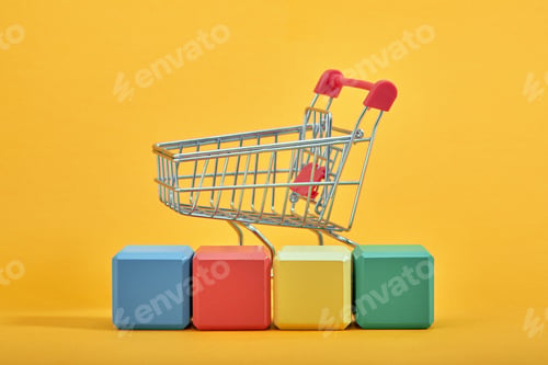 Preview: A miniature shopping cart and wooden blocks with the wordings SALE, isolated against mint background