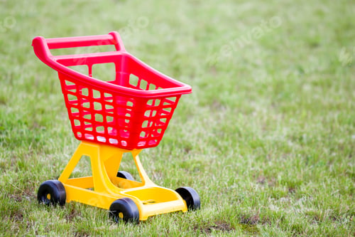 Preview: Bright plastic colorful shopping cart toy outdoors on sunny summer day.