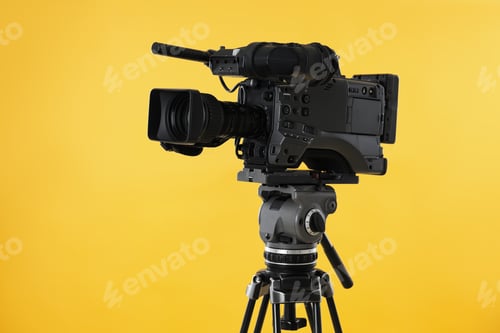 Preview: Modern professional video camera on yellow background