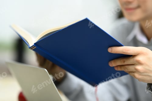 Preview: Smiling university student man reading book, preparing for exams.
