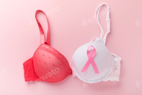 Preview: Breast Cancer Awareness Ribbon. White and red bra with pink ribbon tape lying on female bra on backg