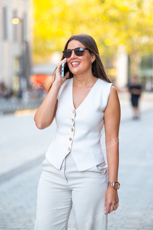 Preview: Businesswoman walking and talking on phone in the city