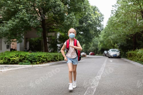 Preview: Little caucasian girl with blonde hair wearing backpack and protective face mask when goes to school