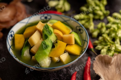Preview: Kaeng Liang in a bowl with spices on a black cement floor.