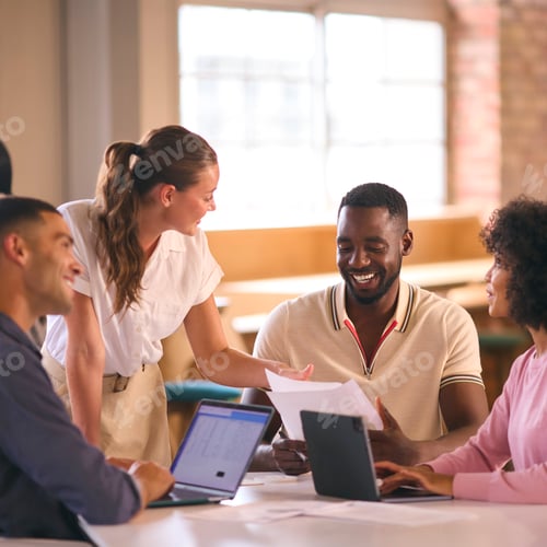 Preview: Multi-Cultural Business Team Meeting Around Desk In Modern Open Plan Office Discussing Documents