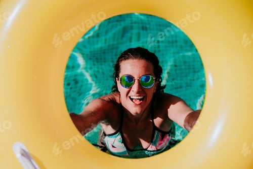 Preview: top view of happy young woman in a pool holding a yellow donuts. summer and fun lifestyle