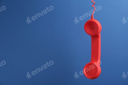 Preview: Red corded telephone handset hanging on blue background, space for text. Hotline concept