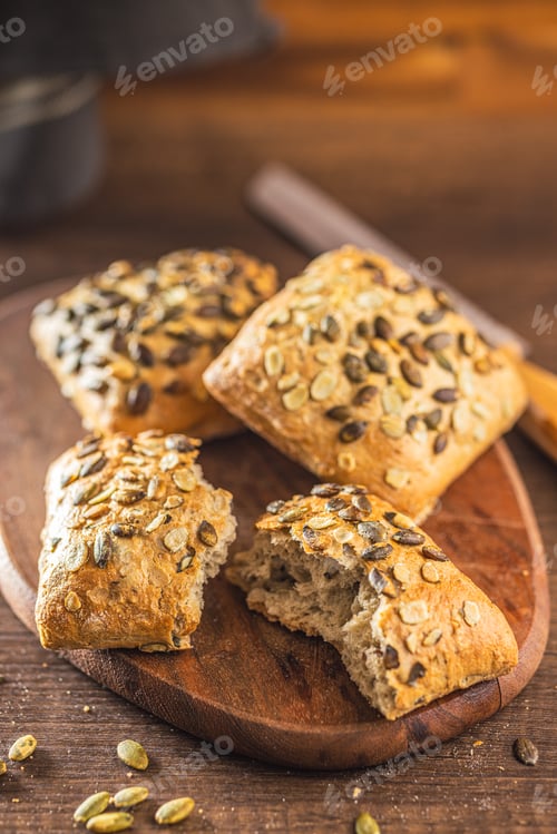 Preview: Whole grain bun with pumpkin seeds on wooden table.
