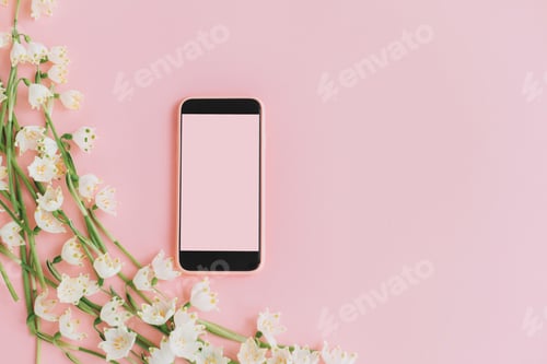Preview: Pink smartphone with empty screen and white spring flowers on pink flat lay