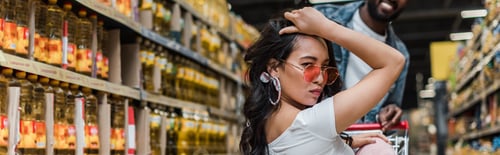 Preview: panoramic shot of african american man near stylish asian girl in sunglasses in store