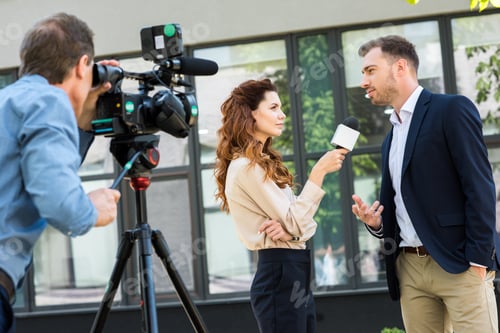 Preview: professional cameraman and journalist interviewing businessman near office building
