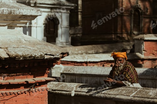 Preview: A indigenous Hindu man wearing a traditional hat pointing a finger towards the camera while smiling