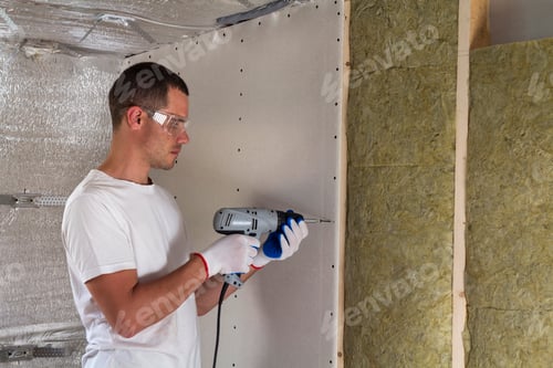 Preview: Worker in goggles with screwdriver working on insulation.