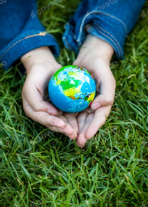 Preview: girl holding Earth in hands against green grass
