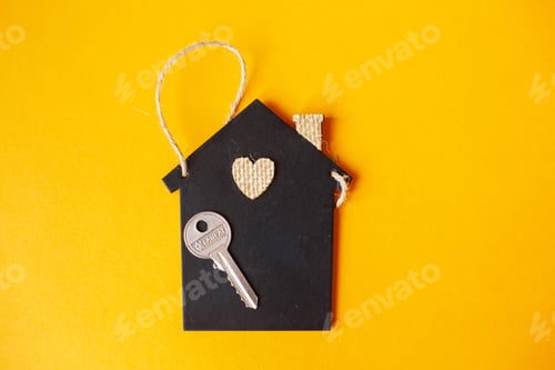 Preview: Little toy house with a key on a orange background.