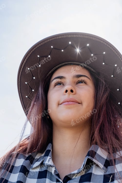 Preview: beautiful woman in plaid shirt and cowboy hat resting on haystack